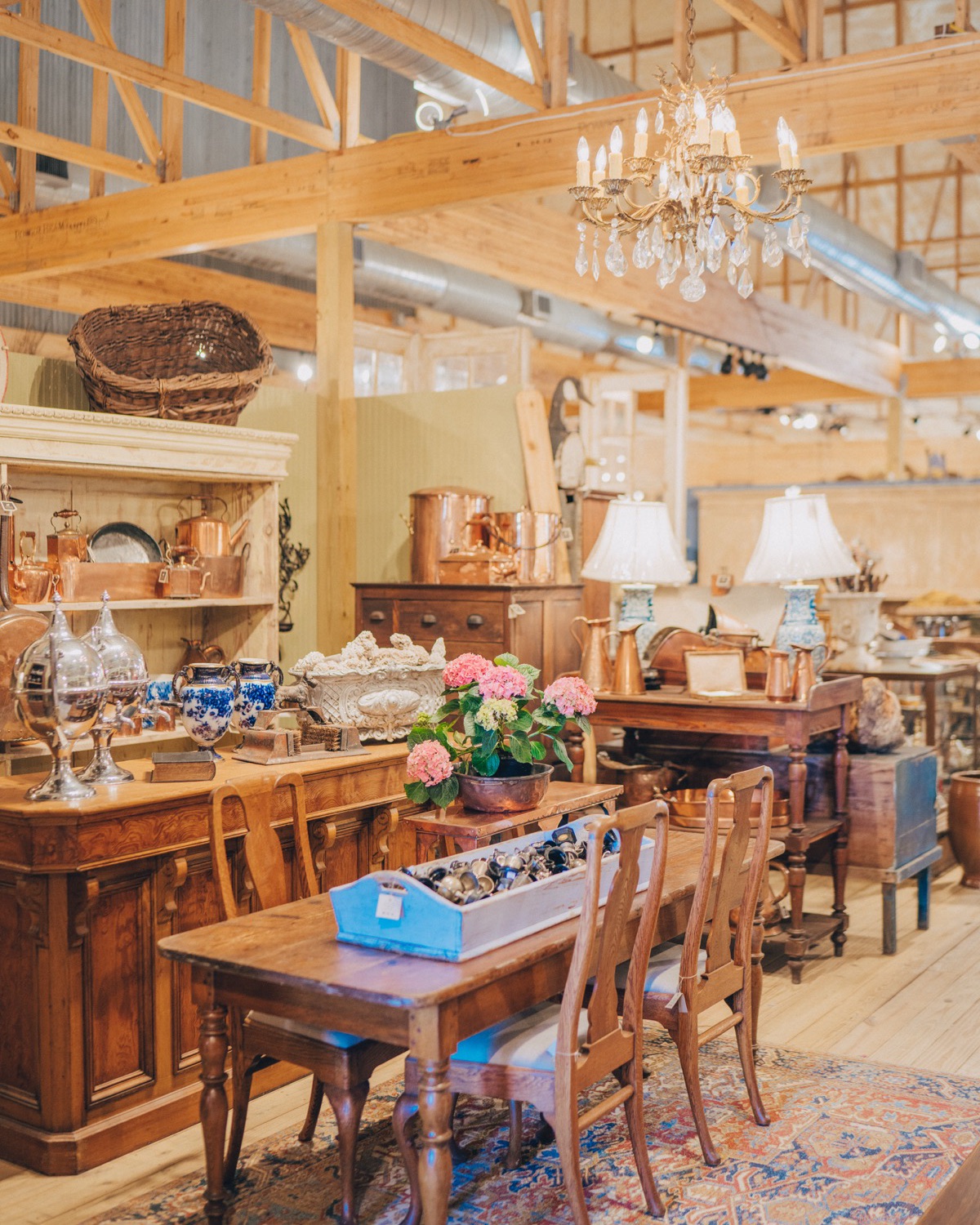 Copperware, a crystal chandelier, and a farm table in an airy pole barn